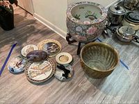 Full lot overview showing the two planters and the eight decorative plates arranged on the floor.