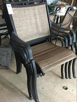 Side chairs stacked, showing black metal frames and beige fabric seats and backs with armrests