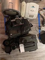 Overview of all lot items arranged on floor: two camera bodies, four lenses, karaoke machine, telephone with CD player