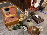 Overall view showing jewelry box, various figurines, trinket boxes, Dutch wooden shoes, Enesco music box, and decorative metal bowl arranged on the floor.