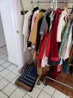 View of hanging girls clothing with a blue blanket on floor beneath rack