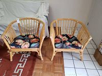 Pair of rattan chairs with navy floral cushions placed on parquet and tile flooring, showing front view.