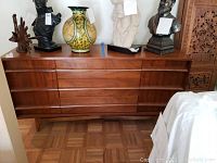 Front view of walnut veneer buffet with three central drawers and cabinets on either side, top surface with items (not included)