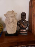 Two bust sculptures side by side on a wooden surface, showing the overall appearance and scale of both items.