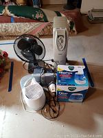 Photo showing Tatung desk fan, Cuori and Holmes heaters, Vicks and Duracraft humidifiers, Black & Decker iron in a basement setting
