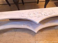 Two wooden valence palmets stacked showing the carved decorative centers and the whitewashed finish