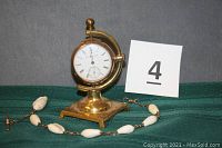 Full view of Elgin pocket watch on brass stand with shell watch fob visible alongside.