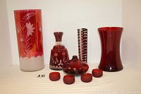 Full lot of six ruby and cranberry colored glass items shown together on white background.