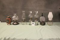 Group view of seven vintage oil lamps arranged in a row on a table