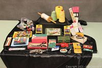 Full overview of sewing supplies arranged on black fabric background showing bulk and packaged items.