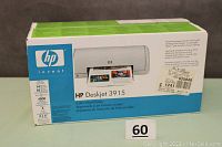 Photo of the original sealed box showing the HP Deskjet 3915 printer branding and partial image of the product.