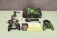 Original Xbox console with lightning bolt design and two controllers alongside power and AV cables plus player pamphlet.
