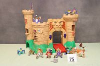 Fisher Price Great Adventurer Magic Castle with 14 figures arrayed in front showing full castle exterior with lion entrance and flags on towers.