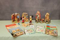 Full lot showing Disney figurines, paper dolls, magazines, puzzles and character books arranged on a table