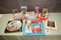 Overview photo showing majority of puzzle boxes in the lot including the Biltmore 750 piece and others stacked on a table.