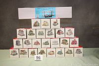 Wide shot of all 24 boxes of miniature buildings arranged in 4 rows with the large shelf box at top.