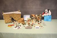 Full view of the lot showing all dog figurines and accessories arranged on table with wicker basket.
