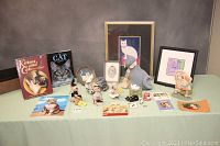 Full display of all items on a table including books, figurines, and framed artwork under good lighting to show the lot contents.