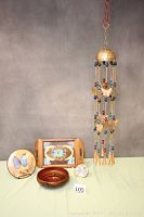 Full view of six butterfly-themed items including a hanging mobile, wooden bowl, wooden tray with butterfly art, and three framed butterfly wing art pieces.