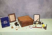 Full view of all vintage desk accessories showing the wooden 2-drawer file box in center, two wooden picture frames, paper holder, opera glasses, ink wells, various small desk items, and carbon paper.