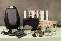 Spa Massage back massage cushion, gray tweed Stetson fedora hat, shoulder bag, wallets, neckties, and assorted small men's items arranged on table.