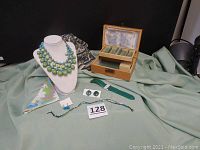 Full lot overview showing multi-strand necklace on display bust, earrings on card, Gossip watch with green band, floral square scarf, flower handkerchief, and wooden music box open showing compartments.