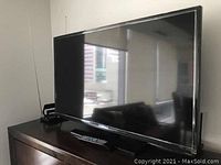 Samsung 46-inch LED TV on stand with remote placed on top, set against an office window background.