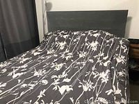 Queen size bed set showing dark wood Ikea bed frame and mattress covered by a floral comforter (not included).