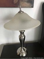 Full view of the 23-inch stainless steel table lamp with frosted glass wide shade, showing metallic base and textured glass top.