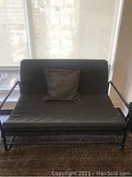 Front view of Ikea Hammarn futon sofa bed with dark gray upholstery and matching cushion, showing sitting surface and backrest.