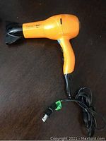 Side view of orange and black Infiniti Pro hair dryer with concentrator nozzle and power cord shown coiled.