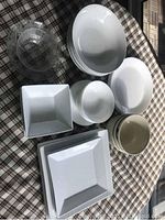 Photo showing assorted plates and bowls in different shapes and sizes including clear glass bowl and white ceramic items.