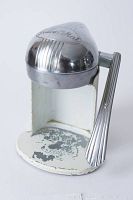 Front-side view showing the polished chrome top with the embossed Juice-O-Mat logo and lever on a painted metal base with visible paint wear.