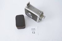 Kodak 8mm film camera and Ricoh flash case placed on white background showing front and side of camera and zipped closed condition of flash case.