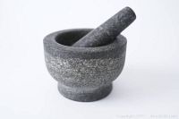 Granite mortar and pestle shown at an angle on white background.