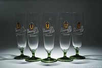 Front view of five tall beer glasses with green bases and Union Pils branding, arranged in a row.