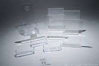 Lot of clear plastic holders including flyer holder, business card holders, and 4x6 photo holders arranged on white surface