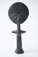 Front view of the Ashanti fertility goddess wooden doll showing large round head, facial details, neck rings, and T-shaped body.