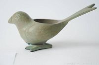 Side angled view of the bird votive candle holder showing the cavity for candle placement and the tail divided at the end.