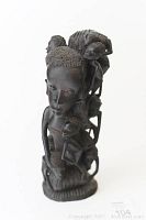 Front view of the tall Makonde carved wooden sculpture showing the facial features of the main figure and parts of the other figures carved around it.