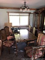 View of four wooden cane-back side chairs and one armchair around a wooden table.