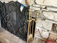 Fireplace screen and brass tool set leaning against a stone fireplace.
