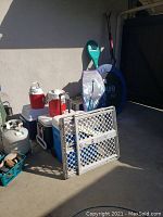 Wide view photo showing all items including coolers, boogie board, trampoline, child gate, tennis racket, skis.