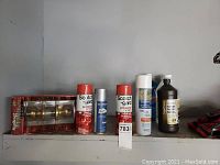 Full view of the shelf showing the door knob packaging and various cleaning spray cans and bottle