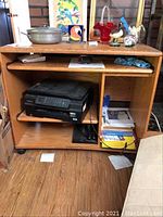Oak computer desk with pullout mechanism, stained surface, open shelves with a Brother printer inside, displayed with various items not included.
