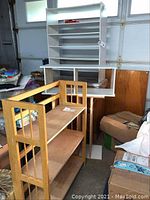 White rectangular multi-shelf unit with four or more levels, set against a garage door background, showing one of the larger stackable bookshelves.