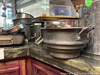 Multiple stock pots stacked on kitchen countertop, showing their handles and metal body.