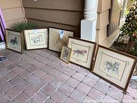 Six framed carousel horse art prints arranged on ground, showing sizes and frames, with visible signatures on some.
