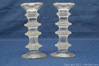 Front view of the pair of glass candle holders showing stacked ring textured design on blue background