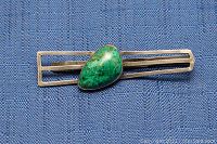 Close-up of vintage 925 sterling silver money clip featuring teardrop-shaped green stone inlay on blue fabric background